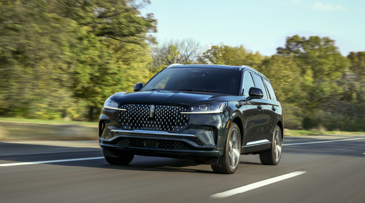 A 2025 Lincoln Black Label Aviator® SUV is being driven down a road lined with trees. | Bill Collins Lincoln of Louisville in Louisville KY