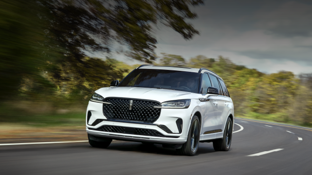 A white 2025 Lincoln Aviator® SUV is being driven down a road lined with trees. | Bill Collins Lincoln of Louisville in Louisville KY
