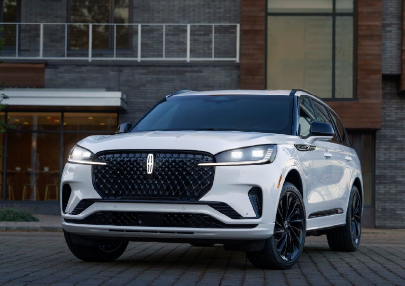 A 2026 Lincoln Aviator® Reserve model is shown with the available Jet Appearance Package parked near a restaurant. | Bill Collins Lincoln of Louisville in Louisville KY