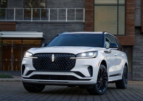 A 2026 Lincoln Aviator® Reserve model is shown with the available Jet Appearance Package parked near a restaurant. | Bill Collins Lincoln of Louisville in Louisville KY