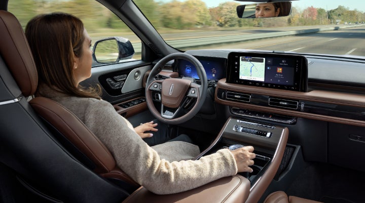 A 2026 Lincoln Aviator® SUV is being driven hands-free on a highway near a forest | Bill Collins Lincoln of Louisville in Louisville KY