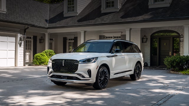 A white 2026 Lincoln Aviator® SUV is parked in the driveway of a luxury home. | Bill Collins Lincoln of Louisville in Louisville KY