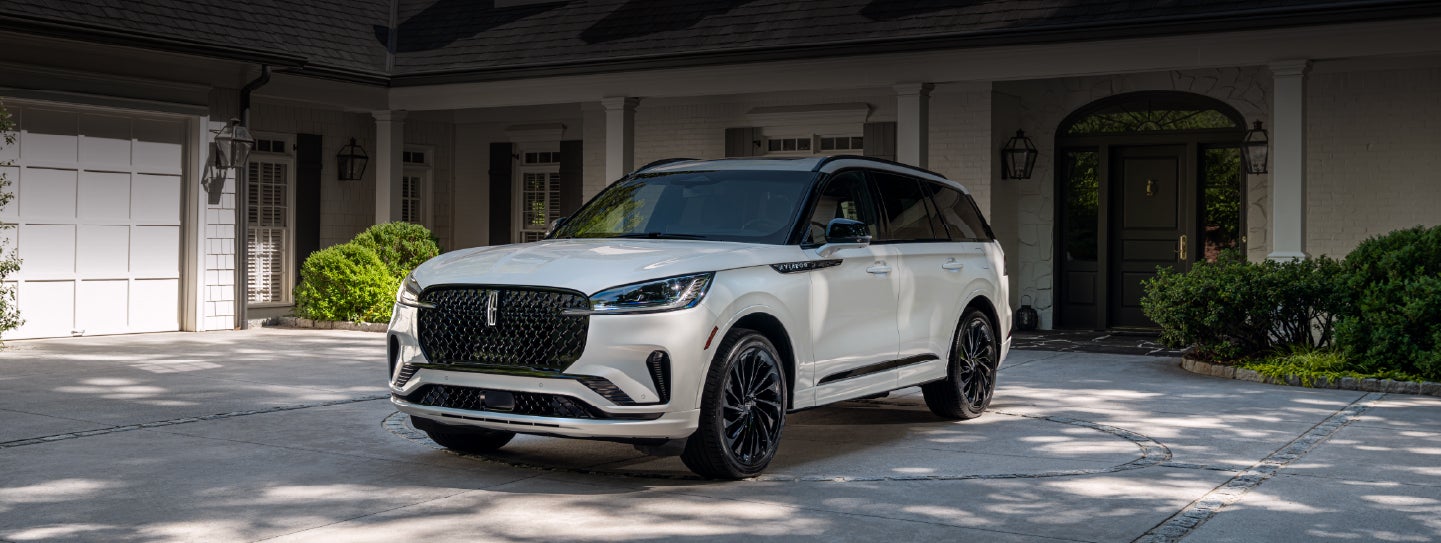 A white 2026 Lincoln Aviator® SUV is parked in the driveway of a luxury home. | Bill Collins Lincoln of Louisville in Louisville KY