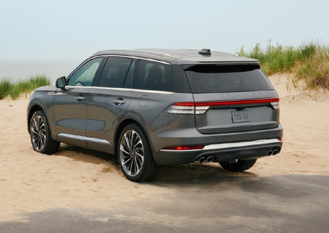 A 2027 Lincoln Aviator® SUV is parked next to sand dunes. | Bill Collins Lincoln of Louisville in Louisville KY