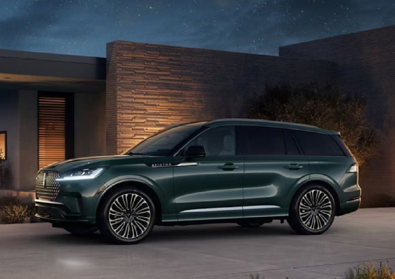 A green 2027 Lincoln Aviator® SUV is parked outside a contemporary home. | Bill Collins Lincoln of Louisville in Louisville KY