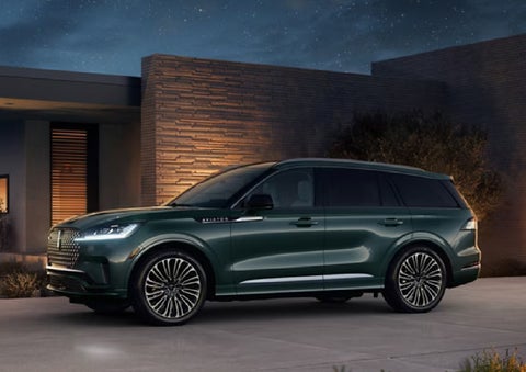 A green 2027 Lincoln Aviator® SUV is parked outside a contemporary home. | Bill Collins Lincoln of Louisville in Louisville KY