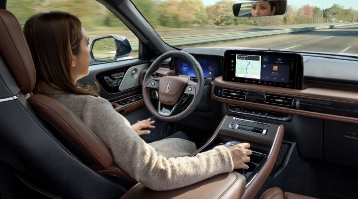 A 2027 Lincoln Aviator® SUV is being driven hands-free on a highway lined with trees. | Bill Collins Lincoln of Louisville in Louisville KY