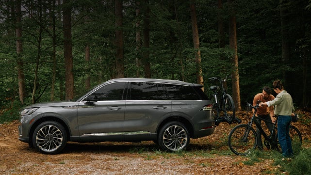 A father and son load e-bikes on a bike rack attached to a 2027 Lincoln Aviator® SUV. | Bill Collins Lincoln of Louisville in Louisville KY