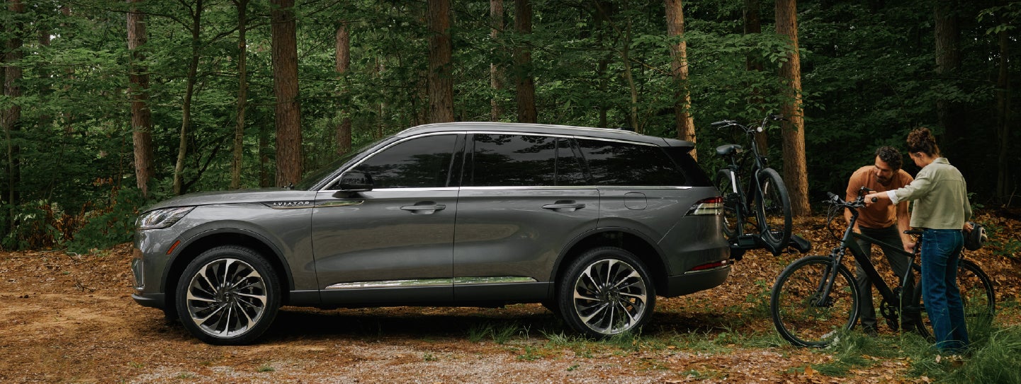 A father and son load e-bikes on a bike rack attached to a 2027 Lincoln Aviator® SUV. | Bill Collins Lincoln of Louisville in Louisville KY
